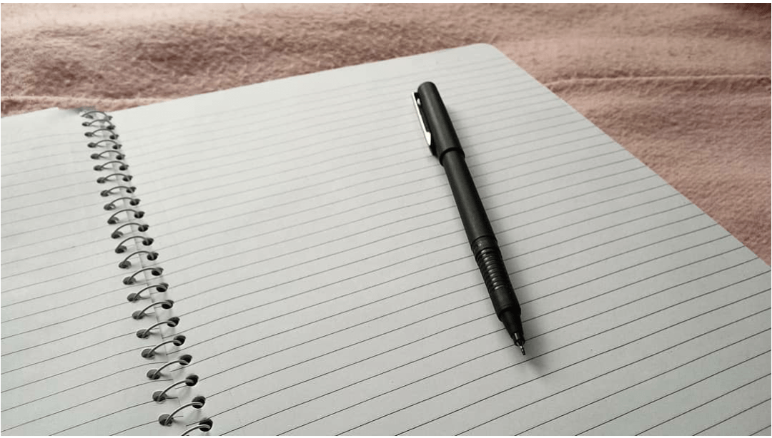 Pen resting on the page of an open notebook.