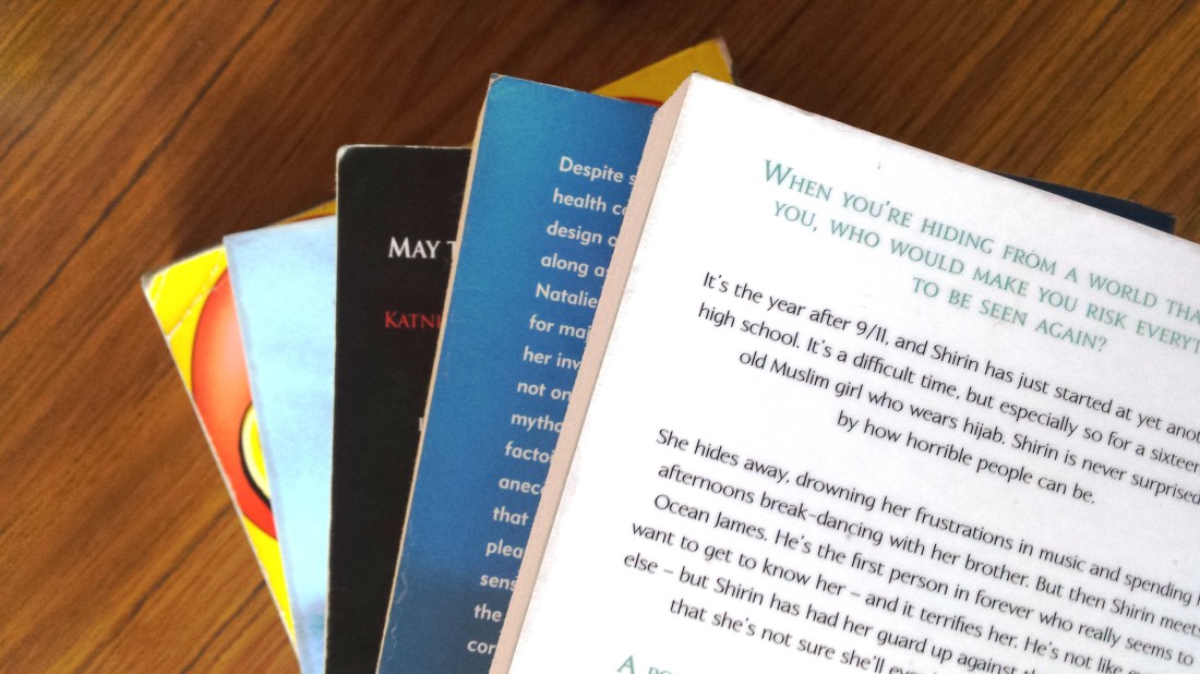 Flatlay of books fanned out on a desk.